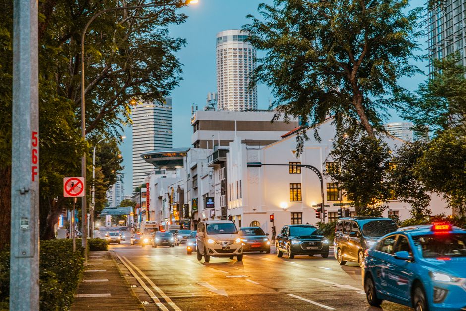 View of a bustling city street at twilight with cars and modern architecture, creating an urban scene.
