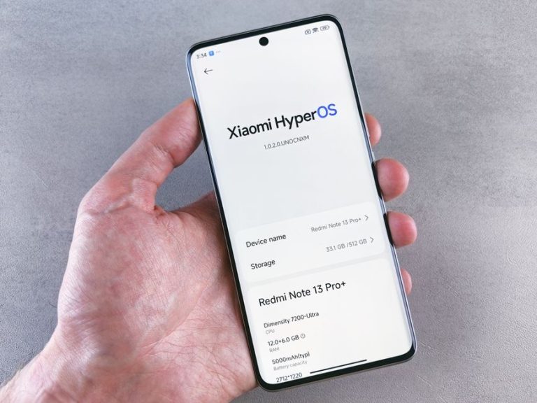Close-up of a hand holding a smartphone displaying Xiaomi HyperOS on the screen.