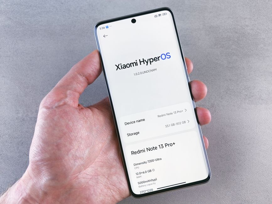 Close-up of a hand holding a smartphone displaying Xiaomi HyperOS on the screen.