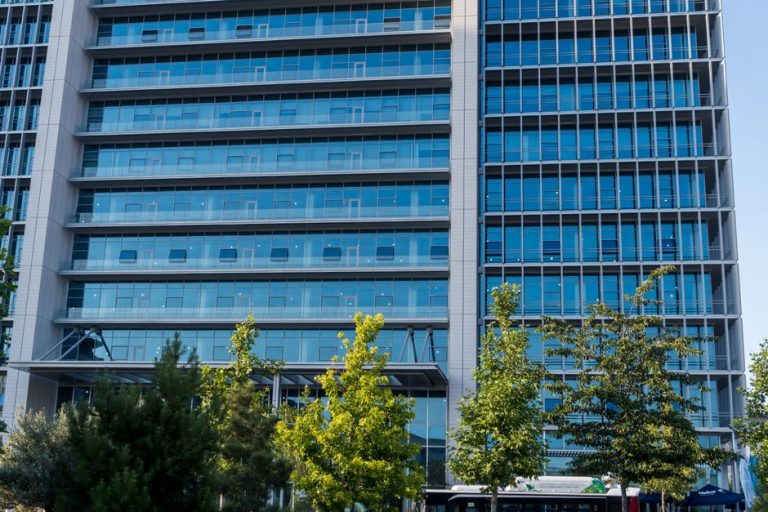 Glass facade skyscraper with trees in downtown urban scene, perfect for business and architecture themes.