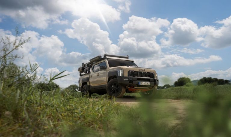 A rugged Kia offroad vehicle navigating a scenic countryside under a partly cloudy sky.