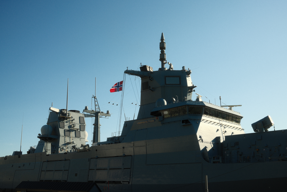 A Norwegian navy frigate with a national flag in daylight.