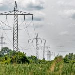 Transmission towers stretch across a lush field in Ingolstadt, Bavaria, Germany.