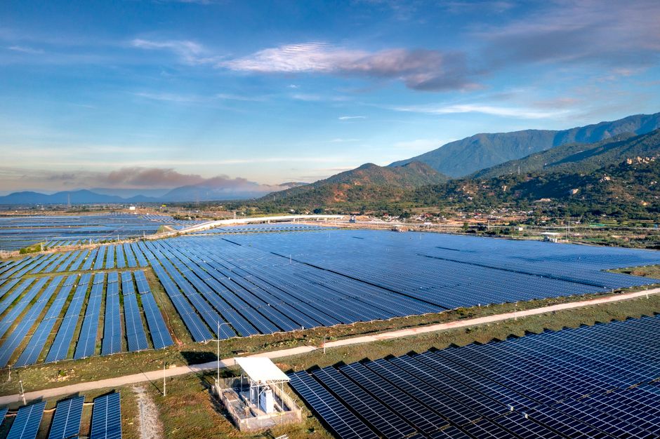 Expansive solar panels in a scenic landscape with mountains, demonstrating renewable energy efforts.