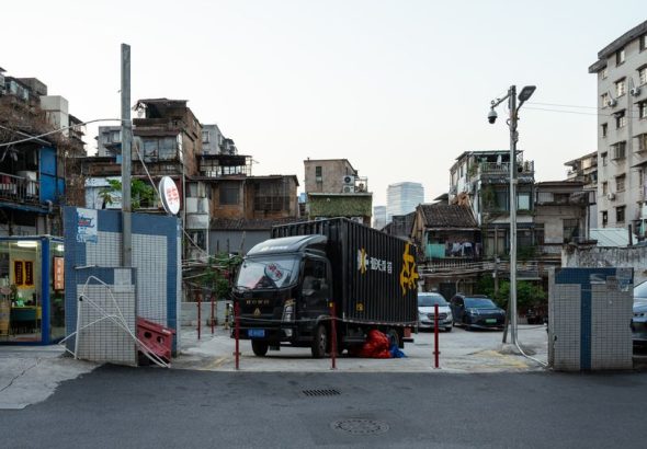 Street scene featuring a black delivery truck and surrounding urban landscape at day.