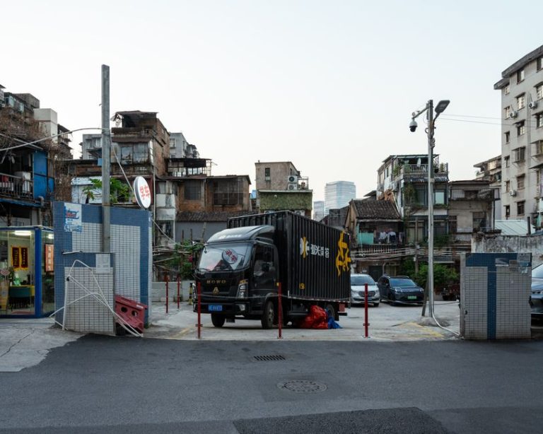 Street scene featuring a black delivery truck and surrounding urban landscape at day.
