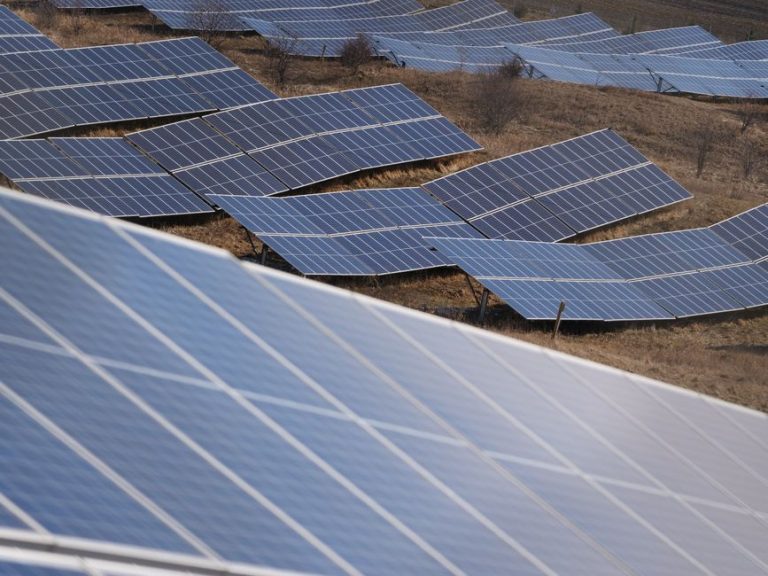 Aerial view of a large solar panel farm capturing sunlight in an open field.