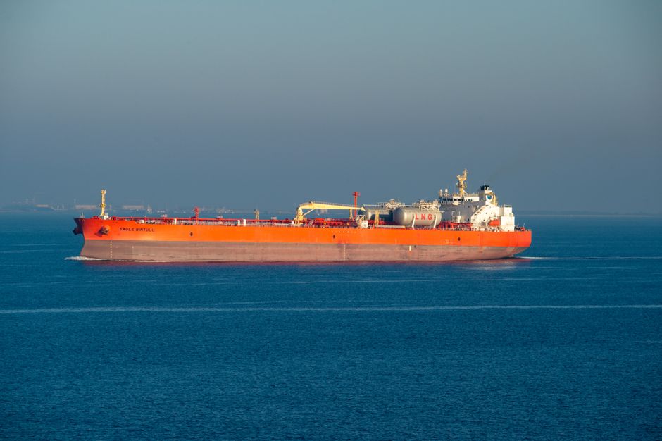 Bright orange LNG carrier ship cruising through calm sea waters on a clear day.