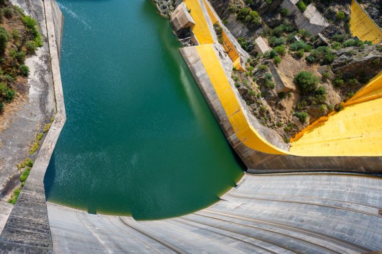 Stunning downward view of a massive hydroelectric dam with vibrant water and concrete structures.