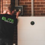 Electrician installing a home energy battery storage unit. Renewable and sustainable energy solution for residential use.