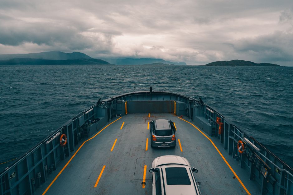View from a ferry with cars on deck traveling through Norway's fjords.