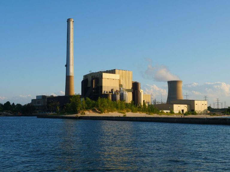 View of Michigan City power plant at dusk beside the waterfront, under a clear blue sky.