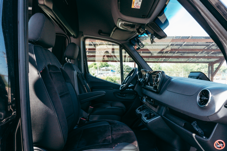 Explore the sleek interior of a luxury van with plush black leather seating and high-end amenities.