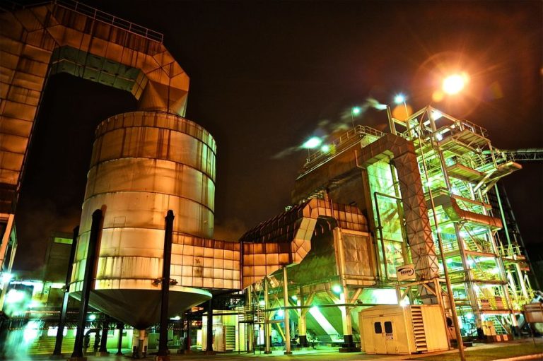 A glowing industrial structure illuminated at night, showcasing complex machinery.