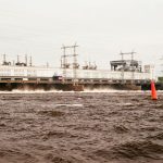 Power plant and river with water flow and industrial infrastructure, showcasing energy production.