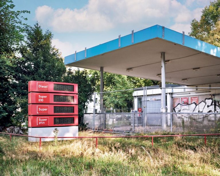 A deserted gas station with graffiti and overgrown grass in Hamburg, Germany.