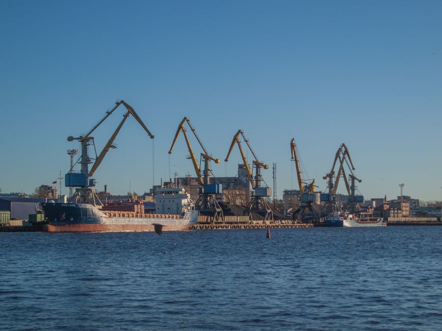 Image of an industrial shipyard with cranes and ships on a sunny day.
