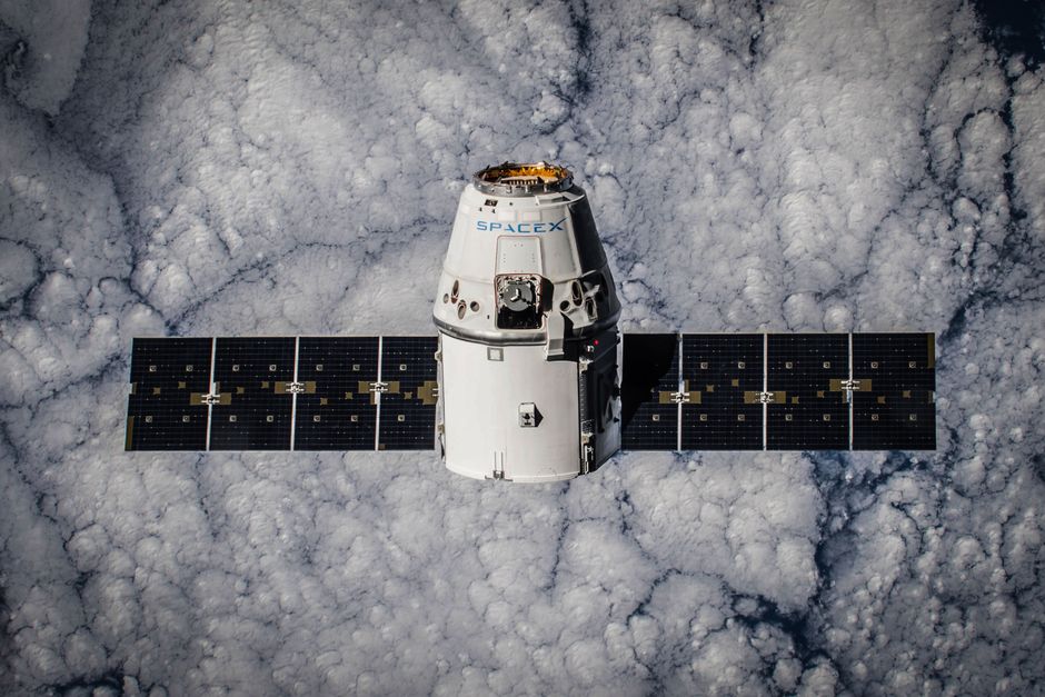SpaceX Dragon spacecraft in orbit, highlighting advanced space technology with cloud backdrop.