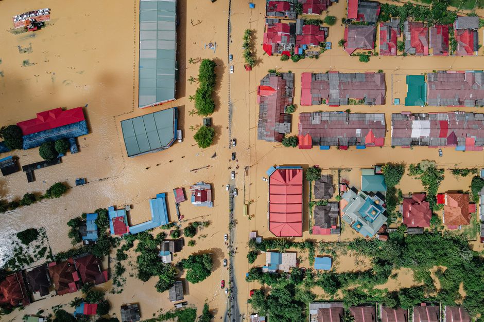Top view of small residential buildings and verdant lush trees in flooded village