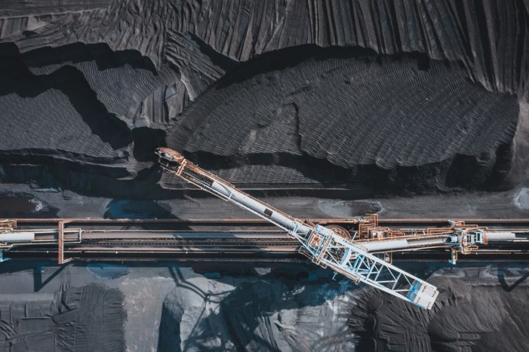 Top view of modern industrial machinery working with black natural coal in daylight