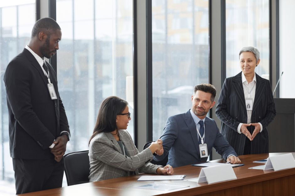 A diverse group of professionals shaking hands during a business meeting in a modern office.