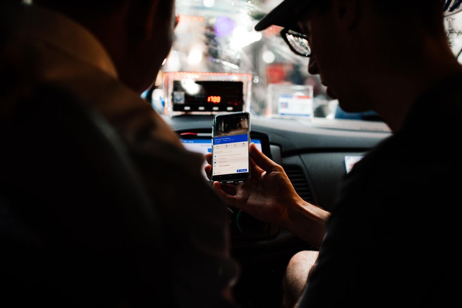 Two people using a smartphone for directions in a car at night.