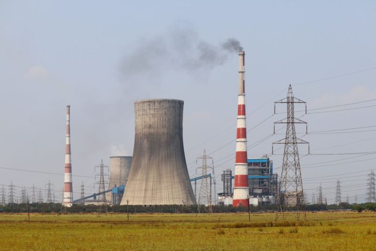 Smokestacks and a cooling tower emit smoke at a power plant in Vijayawada, India.