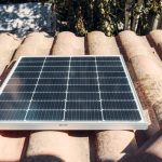 A single solar panel on a rustic tiled roof gleaming in sunlight. Eco-friendly energy.