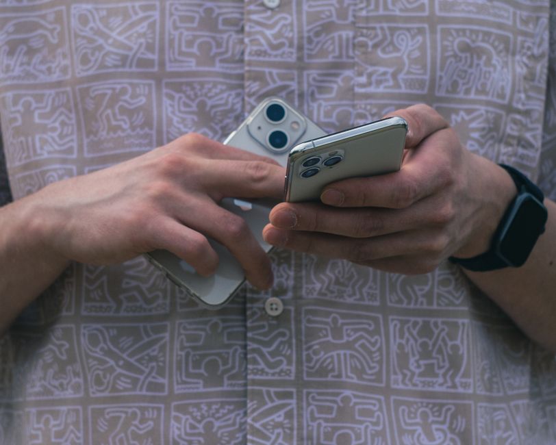 Detail of hands holding two smartphones, showcasing modern technology usage.
