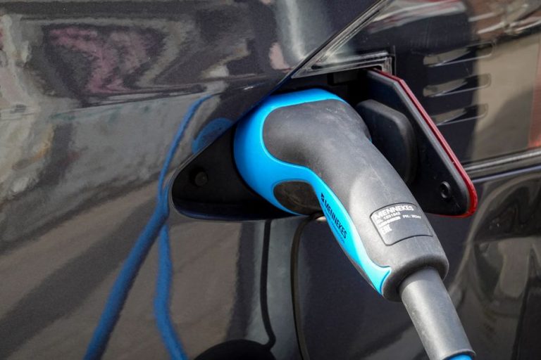Close-up of an electric vehicle being charged using a Mennekes EV connector.