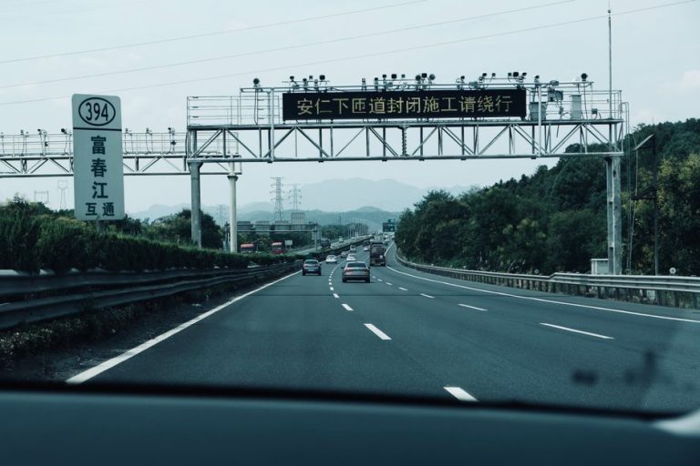 A busy highway in Asia with traffic signs and cars on a cloudy day.