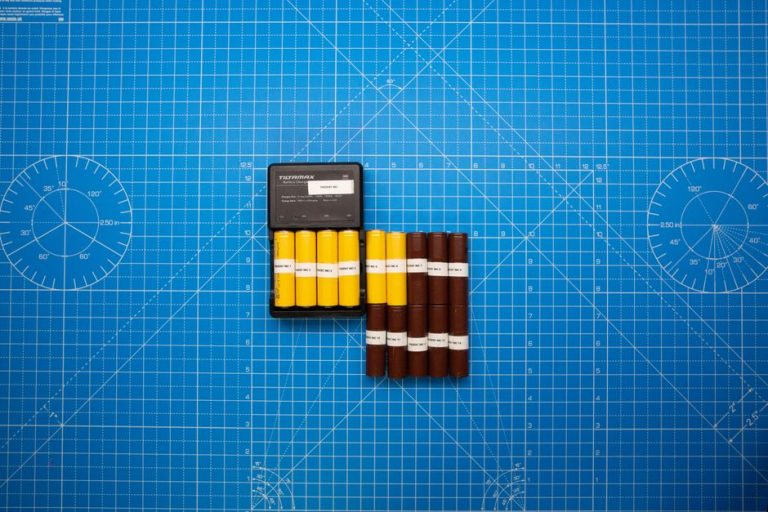Top view of batteries on a blue grid design surface with a charger, showcasing organization and technology.