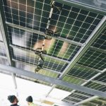 Close-up of solar panels being installed outdoors with technicians visible.
