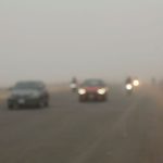 Vehicles drive through dense fog on a highway in Dhaka, Bangladesh during winter.