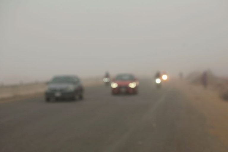 Vehicles drive through dense fog on a highway in Dhaka, Bangladesh during winter.
