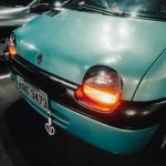 Detailed view of a Renault Twingo's headlights glowing in a parking lot at night, capturing its iconic design.