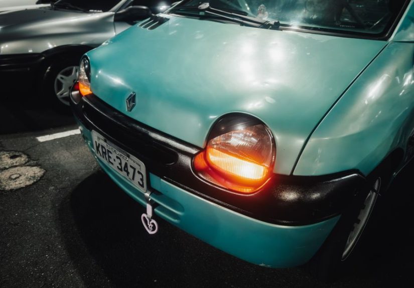 Detailed view of a Renault Twingo's headlights glowing in a parking lot at night, capturing its iconic design.