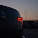 A close-up of a car's taillight glowing red against the evening sky.