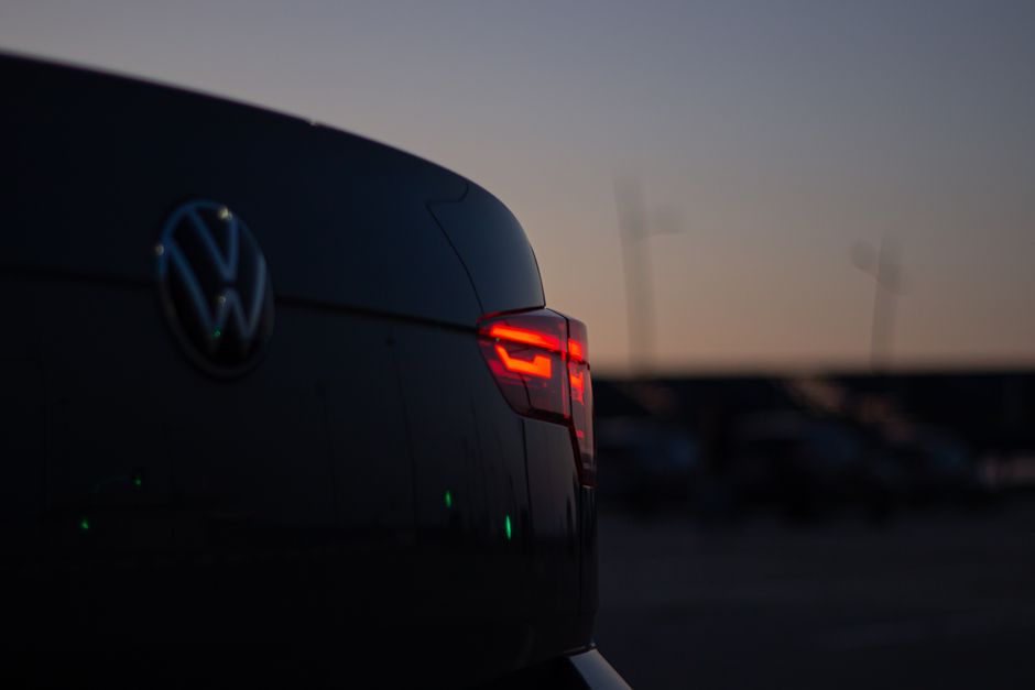 A close-up of a car's taillight glowing red against the evening sky.