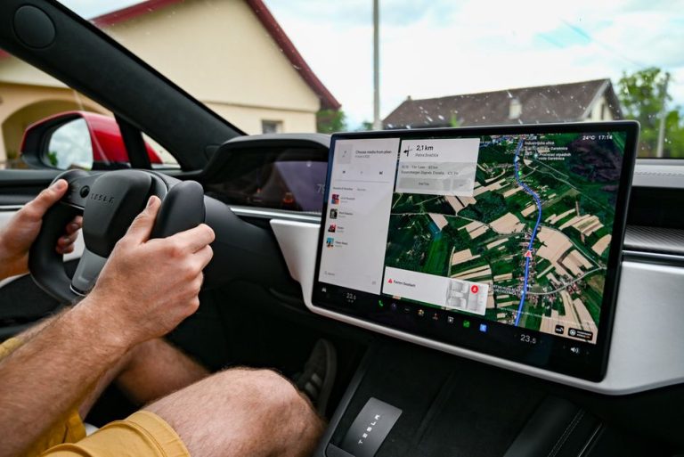 Man driving Tesla using GPS on touchscreen dashboard for navigation.