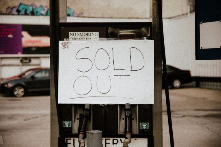 A gas pump at an urban station displaying a 'Sold Out' sign, illustrating fuel shortage.