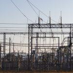 High-voltage electrical substation with steel structures and power lines at dawn.