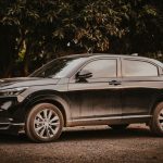 A stylish black Honda HR-V SUV parked outdoors amongst trees on a sunny day.