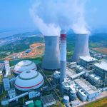 Aerial shot of a power plant with cooling towers emitting steam in Jiujiang, China.