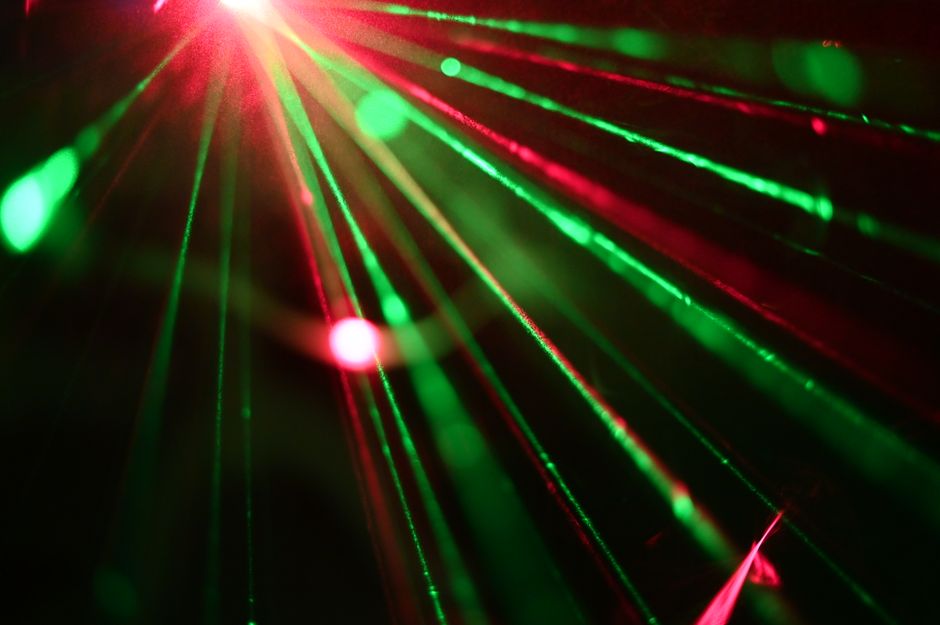 Dynamic display of red and green laser lights creating vivid rays across a dark background.