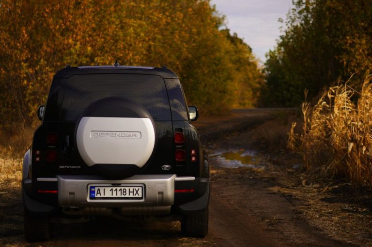Black SUV on a dirt road surrounded by autumn foliage, showcasing adventure and exploration.