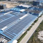 Aerial photograph showcasing large solar panels installed on an industrial building complex.