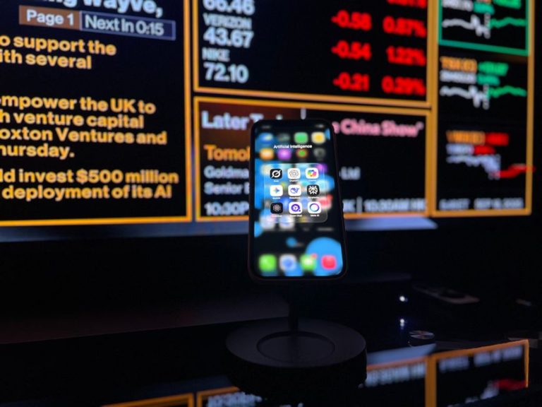 Smartphone displaying AI apps in front of a financial data screen in London.