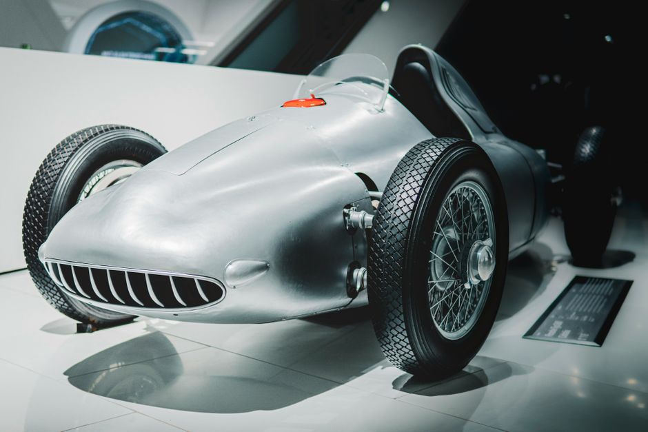 Vintage race car on display in a modern museum setting. Ideal for historical automotive concepts.