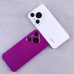 Two Huawei smartphones, one white and one purple, on a textured concrete surface.